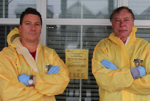 Owner Standing Arms Crossed With His Certified Hazmat Technician Wearing Yellow Suit