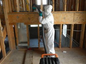 Technician in PPE vacuuming home under construction