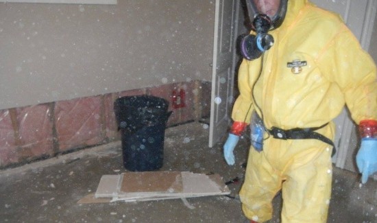 Hazmat technician in PPE cleaning dust filled room